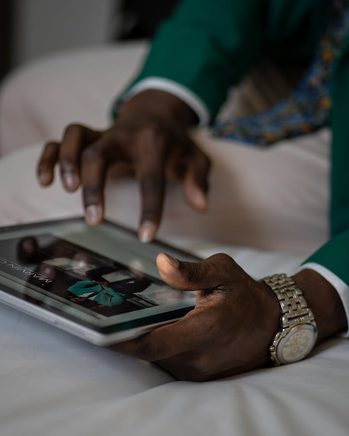 Close-up of a man interacting with a tablet on his bed, showing digital engagement.