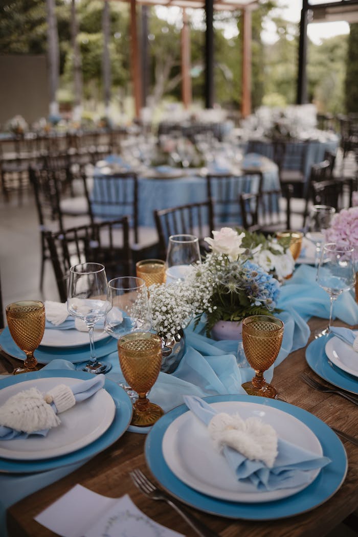 Beautifully decorated outdoor wedding reception table with blue theme and floral centerpiece.