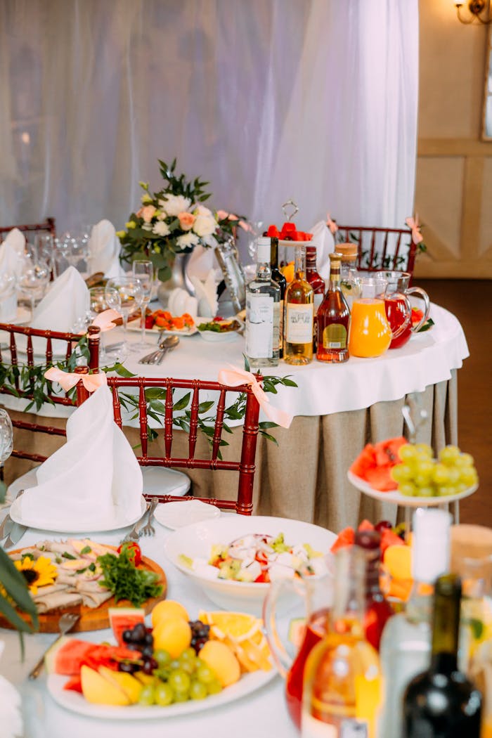 Luxurious banquet table adorned with drinks, flowers, and assorted appetizers in an elegant setting.